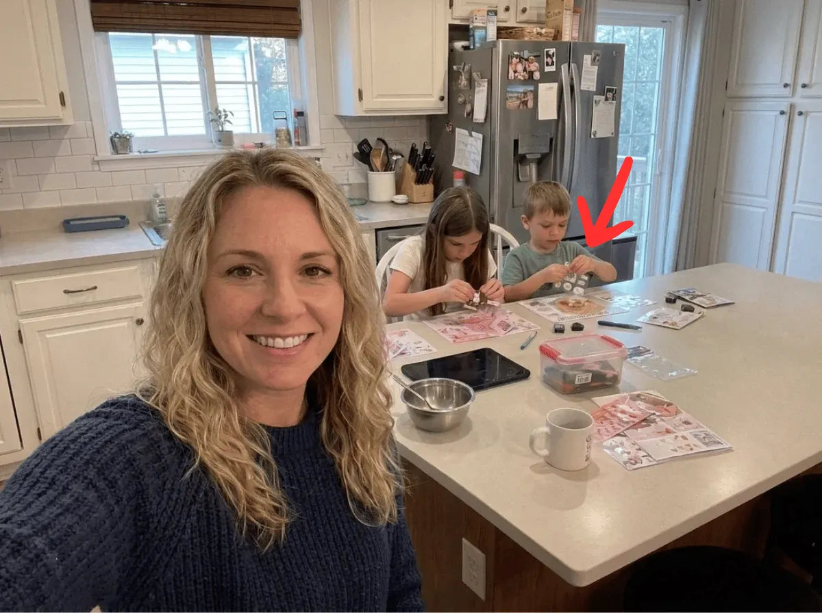 A mother and two children building GOODVIBESUMMER miniature scenes together at a kitchen island
